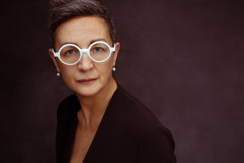 portrait of woman wearing distinctive white eyeglasses, featured photographer sue bryce education